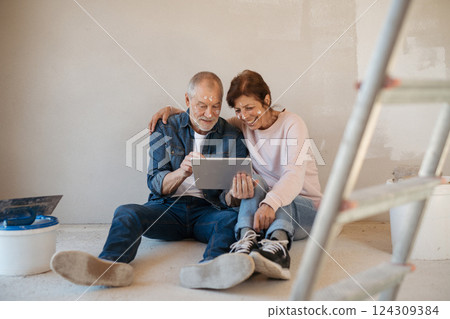 Senior couple renovating their home, browsing for inspirations on tablet. 124309384