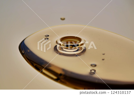 Texture of pouring cosmetic oil on a golden background. 124310137