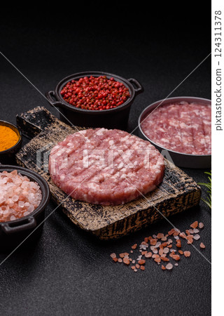 Fresh raw ground beef or pork burger patty with salt and spices 124311378