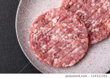 Fresh raw ground beef or pork burger patty with salt and spices Fresh raw ground beef or pork burger patty with salt and spices 124311383
