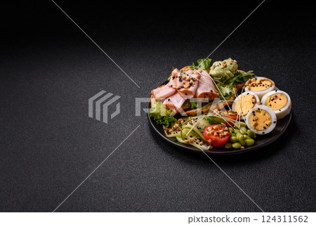 Healthy breakfast consisting of boiled eggs, slices of ham, tomatoes, green beans, aioli sauce 124311562