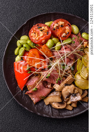 Warm salad consisting of slices of roast beef, greens, tomatoes, cucumbers, green beans 124311601
