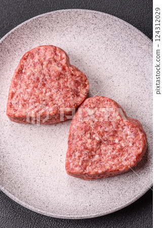 Raw beef or pork burger patty in the shape of a heart 124312029
