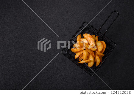 Baked potato wedges with cheese and herbs on a dark background Baked potato wedges with cheese and herbs on a dark background 124312038