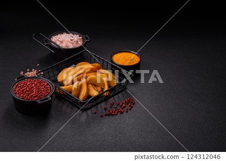 Baked potato wedges with cheese and herbs on a dark background Baked potato wedges with cheese and herbs on a dark background 124312046