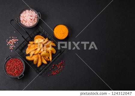 Baked potato wedges with cheese and herbs on a dark background Baked potato wedges with cheese and herbs on a dark background 124312047
