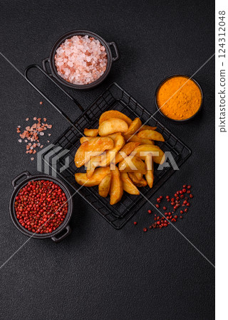 Baked potato wedges with cheese and herbs on a dark background Baked potato wedges with cheese and herbs on a dark background 124312048