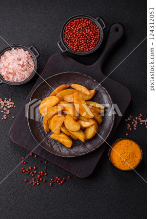 Baked potato wedges with cheese and herbs on a dark background 124312051