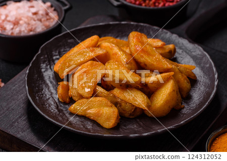 Baked potato wedges with cheese and herbs on a dark background 124312052