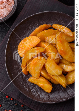 Baked potato wedges with cheese and herbs on a dark background 124312054