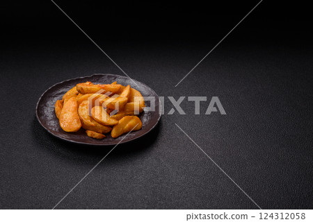 Baked potato wedges with cheese and herbs on a dark background Baked potato wedges with cheese and herbs on a dark background 124312058