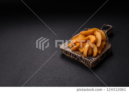 Baked potato wedges with cheese and herbs on a dark background Baked potato wedges with cheese and herbs on a dark background 124312061