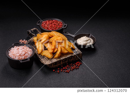 Baked potato wedges with cheese and herbs on a dark background Baked potato wedges with cheese and herbs on a dark background 124312070