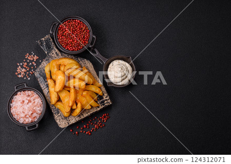 Baked potato wedges with cheese and herbs on a dark background Baked potato wedges with cheese and herbs on a dark background 124312071