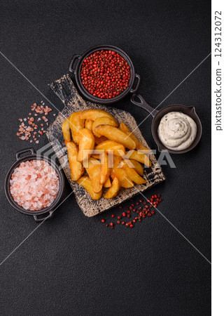 Baked potato wedges with cheese and herbs on a dark background Baked potato wedges with cheese and herbs on a dark background 124312072