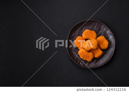 Delicious fresh crispy chicken nuggets on a dark concrete background Delicious fresh crispy chicken nuggets on a dark concrete background 124312216