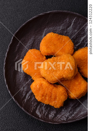 Delicious fresh crispy chicken nuggets on a dark concrete background Delicious fresh crispy chicken nuggets on a dark concrete background 124312220