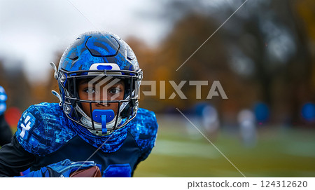 Portrait of young boy playing football, running back moves towards goal propelling team to victory, dynamic moment in high school football game 124312620