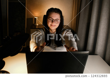 Cheerful millennial woman enjoy videocall with friends using laptop. Gesturing and smiling. Talking with friends who living far. Cherishing long distance friendship. Cheerful millennial woman enjoy videocall with friends using laptop. Gesturing and smiling. Talking with friends who living far. Cherishing long distance friendship. 124312693