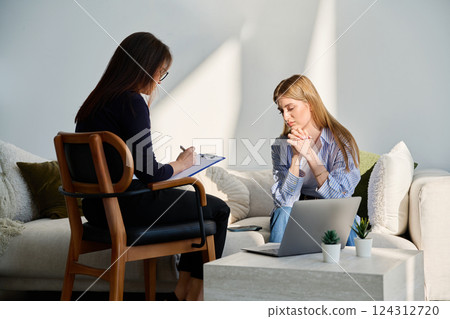 Sad upset young female patient in therapy session in psychologist office Sad upset young female patient in therapy session in psychologist office 124312720