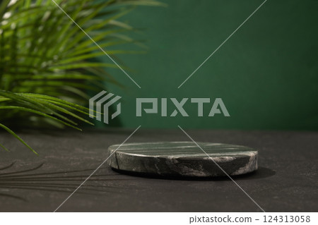 Composition with podium for design your cosmetic products with black marble stand and tropical leaves on green background. Space for design. Composition with podium for design your cosmetic products with black marble stand and tropical leaves on green background. Space for design. 124313058