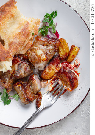 A plate with the remains of a pork kebab, there are no people. 124313226