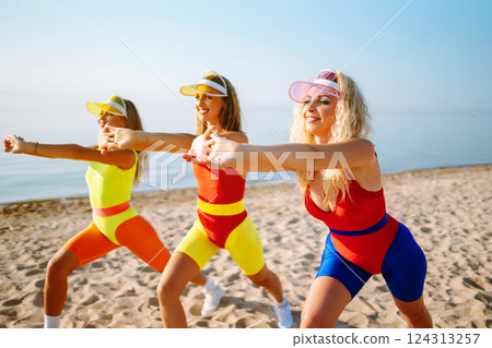 Smiling dancers in colorful swimsuits are dancing on beach ?oncept of sports, aerobics. Active sport 124313257