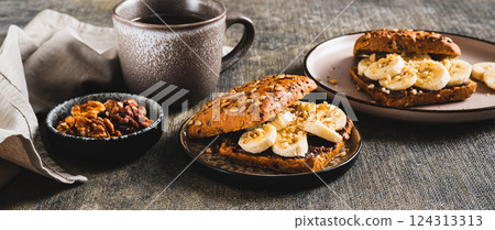 Sweet sandwich with chocolate butter, banana and nuts on a plate on the table web banner Sweet sandwich with chocolate butter, banana and nuts on a plate on the table web banner 124313313