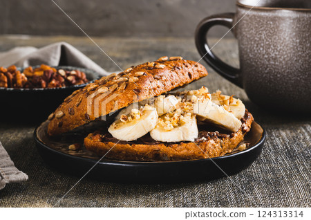 Close up of toast rye bread with chocolate and banana on a plate on the table Close up of toast rye bread with chocolate and banana on a plate on the table 124313314