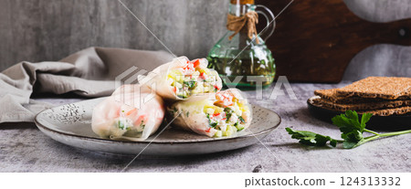 Spring rolls in rice paper with crab sticks, cucumber, greens and sauce on a plate on web banner Spring rolls in rice paper with crab sticks, cucumber, greens and sauce on a plate on web banner 124313332