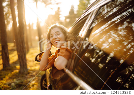 Shot of an attractive woman leaning out of car window while driving. Active lifestyle, travel. 124313528