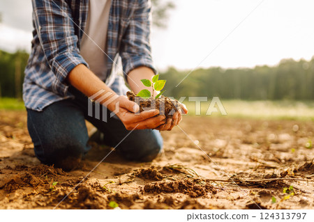 Man in a shirt holds a green plant in his hands. Caring for the environment. 124313797