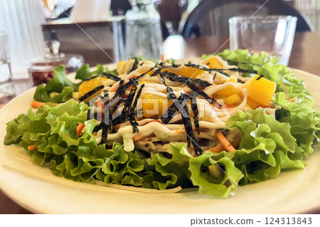 Kani salad with crab, fresh lettuce and mango with vegetables on a plate in a cafe 124313843