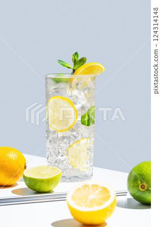 Drink with lemon, mint and ice in a glass on a white blue background with shadow and fruits. 124314148