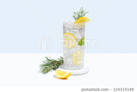 Lemonade with lemon, rosemary and ice in a glass on a white blue background. Summer citrus drink Lemonade with lemon, rosemary and ice in a glass on a white blue background. Summer citrus drink 124314149