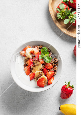 Natural Greek yogurt with homemade chocolate granola, strawberries and banana in a bowl 124314156