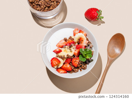Greek yogurt with chocolate granola, strawberries and banana in a bowl on a yellow background Greek yogurt with chocolate granola, strawberries and banana in a bowl on a yellow background 124314160