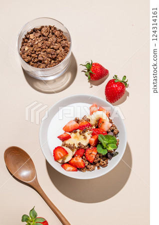 Greek yogurt with chocolate granola, strawberries and banana in a bowl on a beige background 124314161