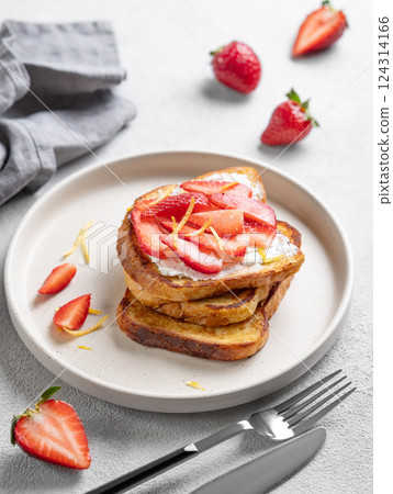 Toasted bread with cream cheese and strawberries on a plate on a light background with fresh berries 124314166