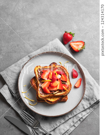Toasted bread with chocolate cream and strawberries on a plate on a dark background Toasted bread with chocolate cream and strawberries on a plate on a dark background 124314170