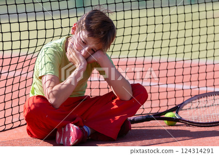 The boy lost the tennis competition. The child sits at the net with a racket. Psychology of sports in childhood. 124314291