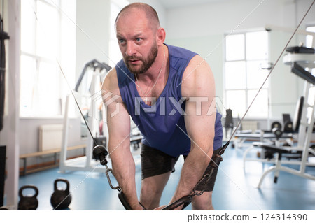 Male athlete bodybuilder exercising in the gym. Strength training on a cable machine. Male athlete bodybuilder exercising in the gym. Strength training on a cable machine. 124314390