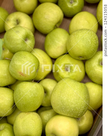 Box filled with fresh juicy natural bio organic green apples placed on counter in local food market. Close-up 124315058