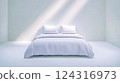White bed in minimalist room with sunlight streaming in 124316973