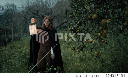 Mystery Of A Woman Walking Among Orchard Trees In Woods At Night With Lantern 124317464