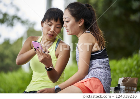 two young asian women female friends relaxing chatting outdoors two young asian women female friends relaxing chatting outdoors 124319210