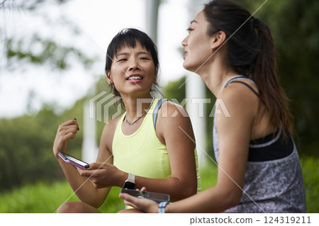 two young asian women female friends relaxing chatting outdoors two young asian women female friends relaxing chatting outdoors 124319211