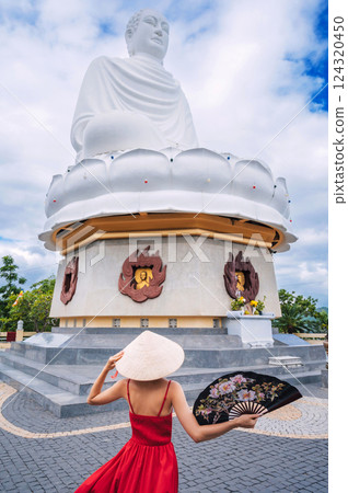 beautiful woman tourist in a Vietnamese hat Buddha statue at Long Son Pagoda in Nha Trang in Vietnam. Tourism and travel in Asia beautiful woman tourist in a Vietnamese hat Buddha statue at Long Son Pagoda in Nha Trang in Vietnam. Tourism and travel in Asia 124320450
