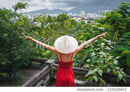 back of happy girl tourist traveler in Vietnamese non la hat in red dress in garden in Vietnam. Tourism and travel in Asia 124320452