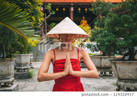 woman tourist traveler in Vietnamese hat prays at Long Son Buddhist Pagoda in Nha Trang in Vietnam. Travel and tourism in Asia 124320457
